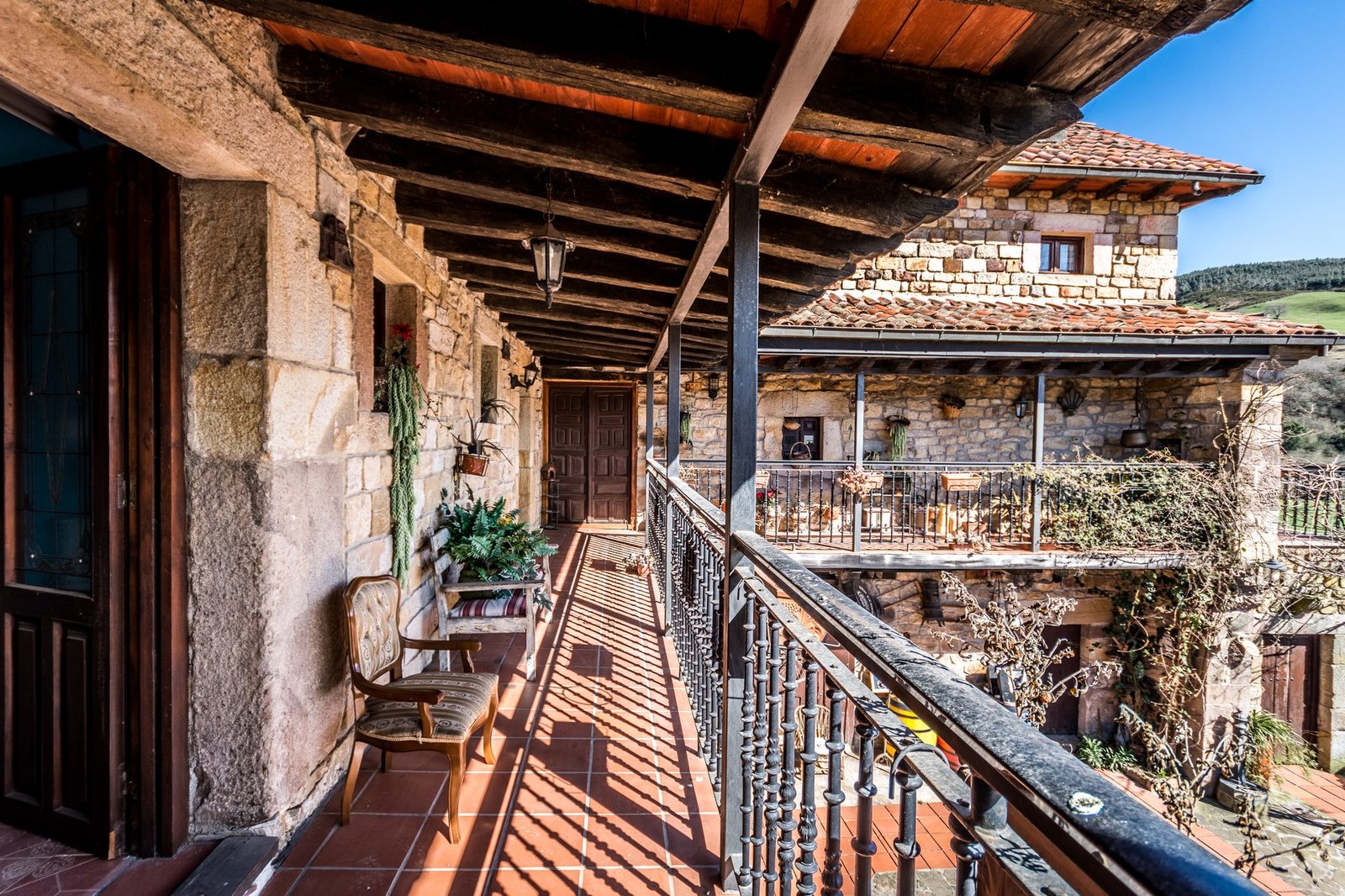 Balcón cubierto de piedra y forja de Finca Gándara con vistas al pueblo